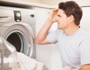 Confused handsome man adjusting the controls of the washing machine