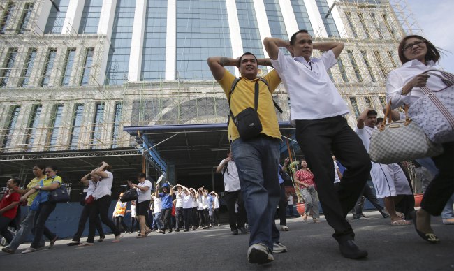 Filipino government workers cover their heads during an earthquake evacuation drill in suburban Makati city, Philippines, Monday, June 30, 2014. City officials said the drill is made to increase awareness on safety guidelines and precautions during an earthquake among government workers. (AP Photo/Aaron Favila)