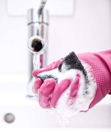 Woman cleaning bathroom sink with sponge
