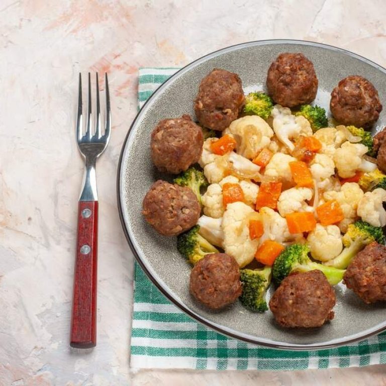 front-view-broccoli-cauliflower-salad-meatball-plate-green-white-checkered-napkin-fork-nude-isolated-background_140725-138826