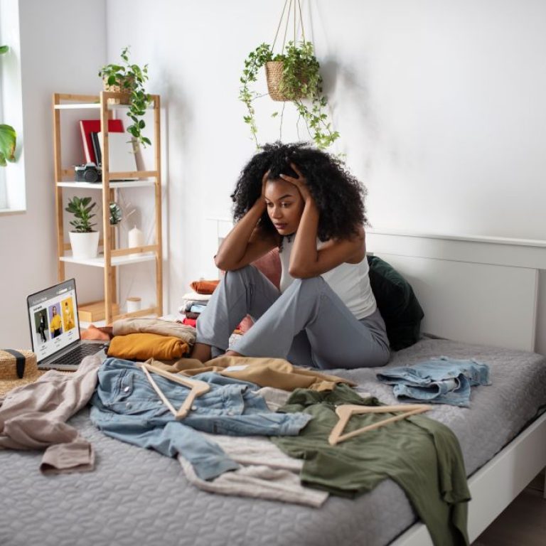 full-shot-woman-sitting-bed-with-clothes