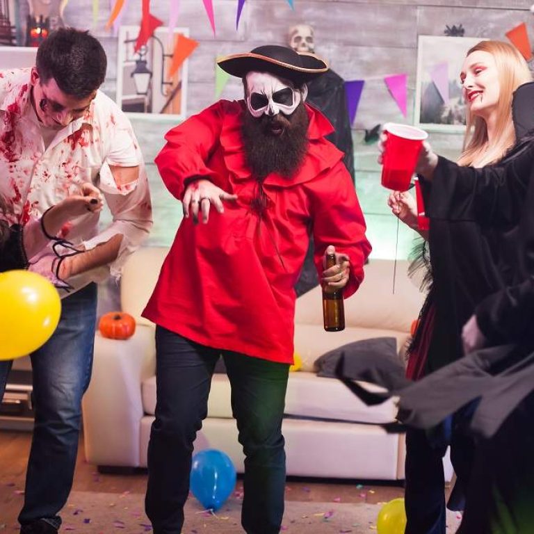 Man dressed up like a pirate dancing around his friends celebrating halloween.